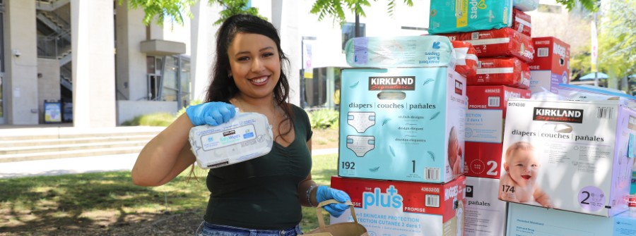 7 of 7, Student leader with blue gloves holding up baby wipes with diapers behind them.