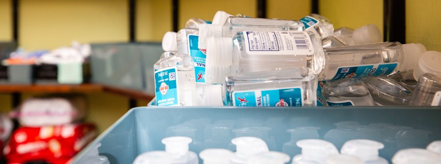 5 of 7, Stack of hand sanitizer bottles in a blue plastic box as part of the personal hygiene program offerings. 