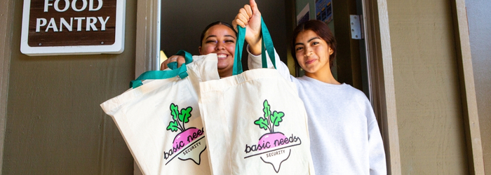 3 of 6, Two staff members holding Basic Needs branded bags 
