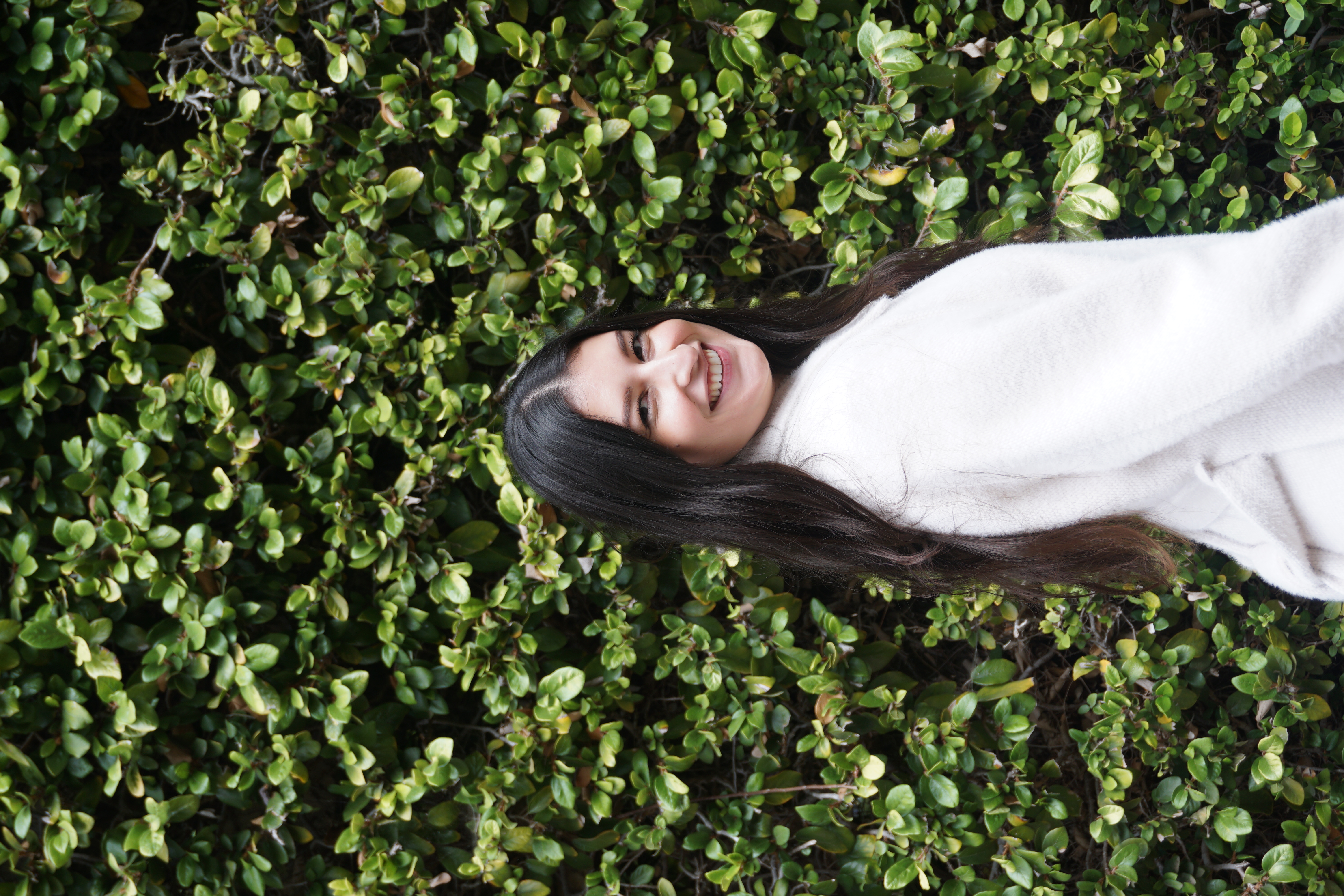 Beatriz Chavez Vega, Food Programs Coordinator, standing in front of a leafy background
