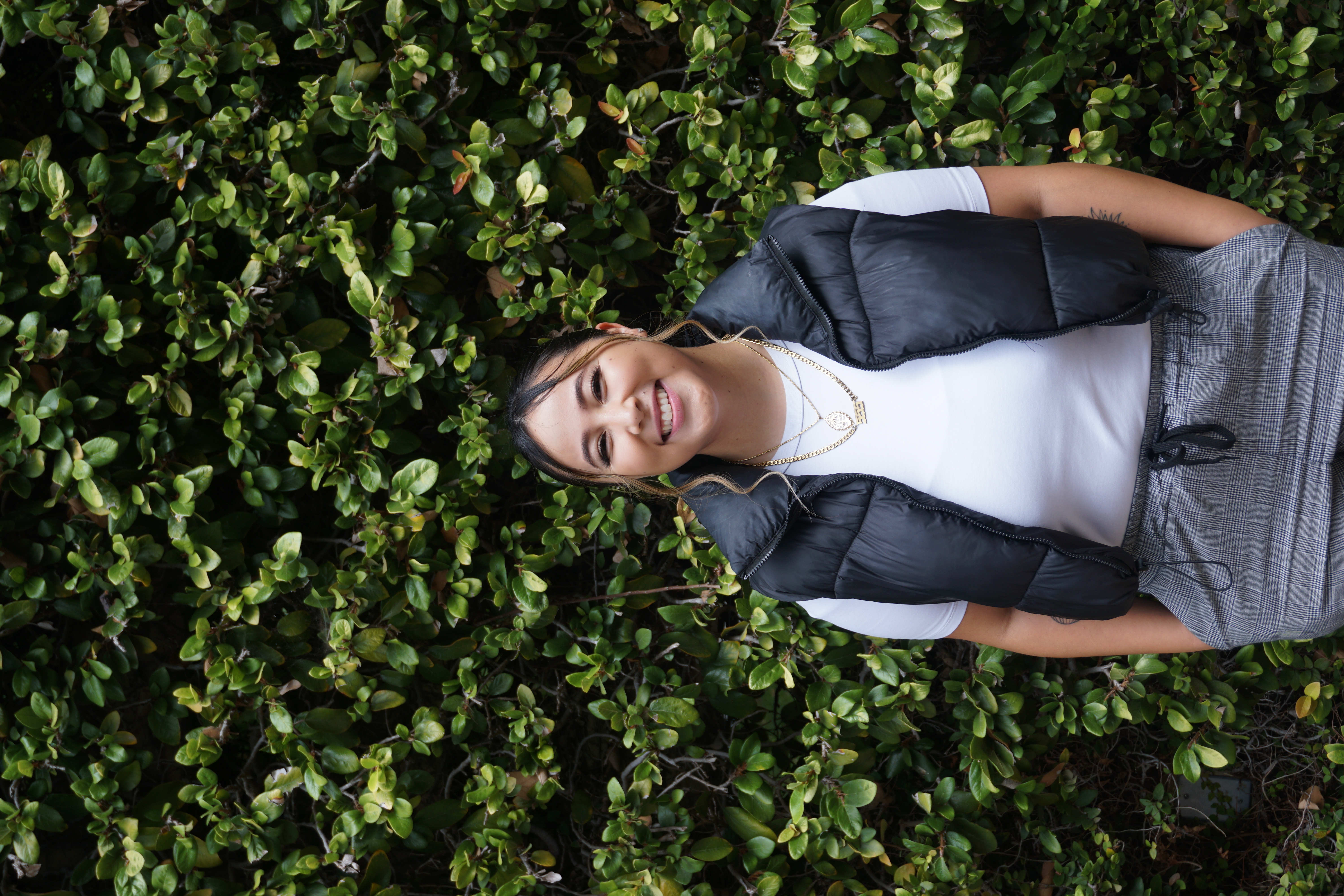 Kameo, Associate Director of Basic Needs, smiling at the camera in front of a leafy background