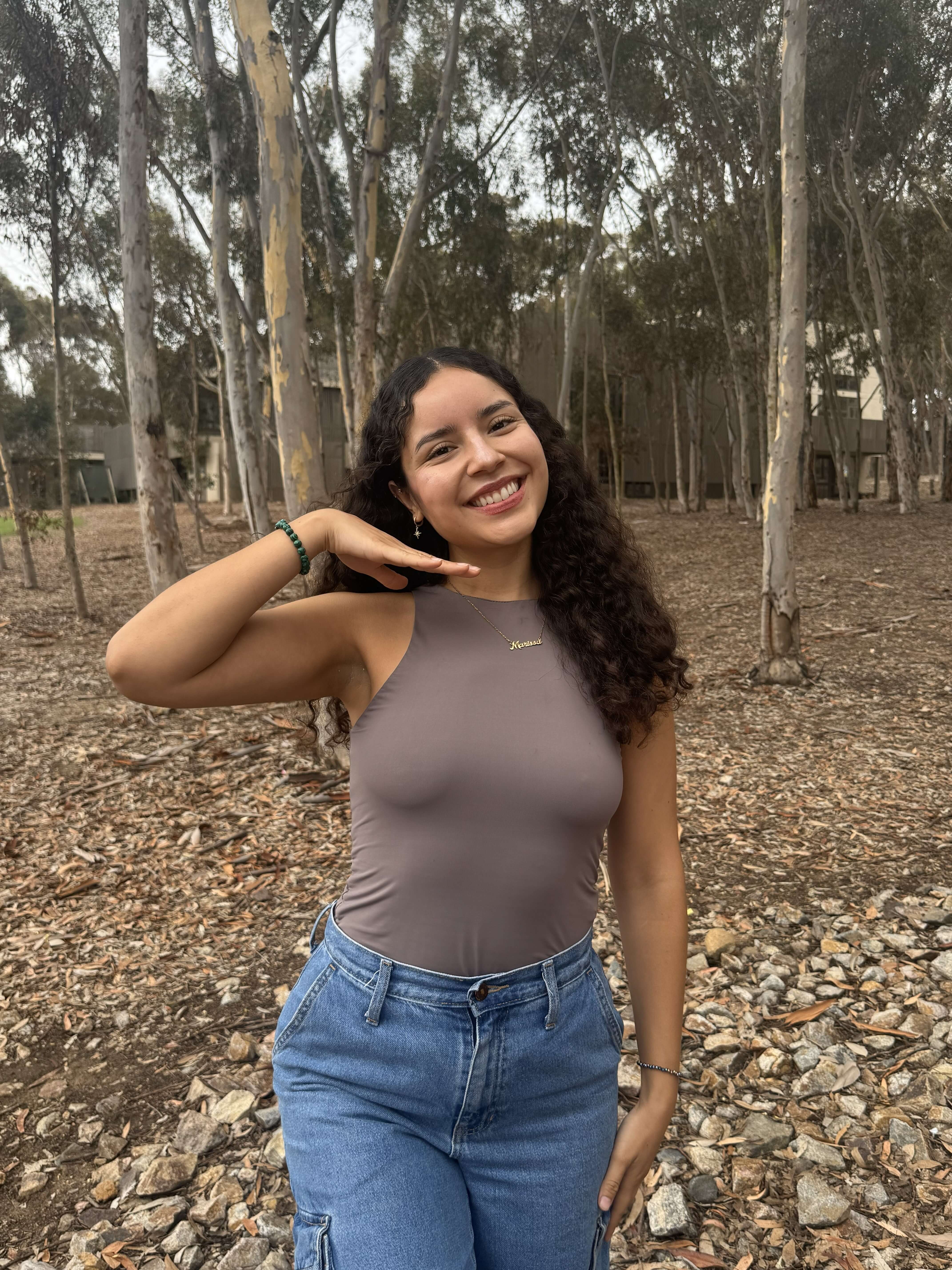 Marissa, Basic Needs Housing & Education Resource Coordinator, smiling at the camera in front of a leafy background